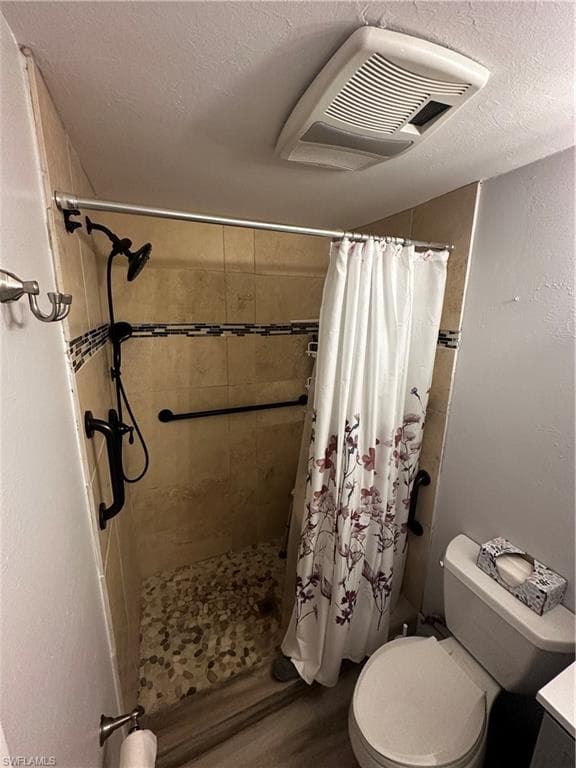 Bathroom with a textured ceiling, a stall shower, vanity, a textured wall, and wood finished floors