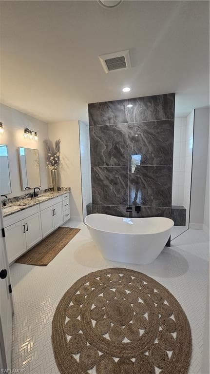 Full bathroom with tile walls, a freestanding bath, and vanity