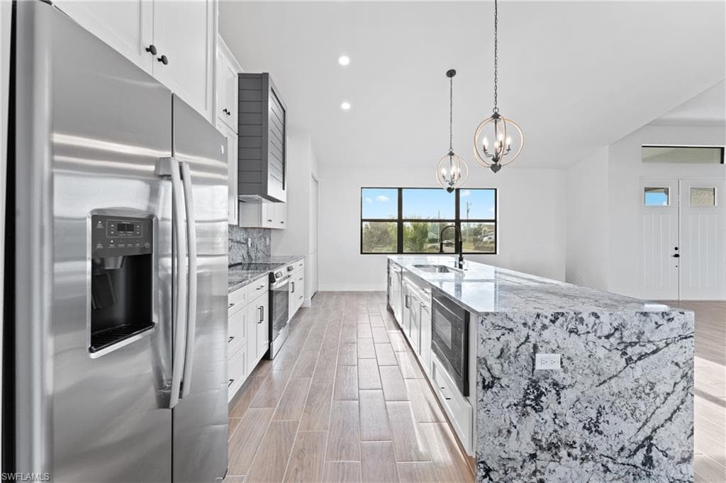 Kitchen featuring stainless steel appliances, light stone counters, and white cabinetry