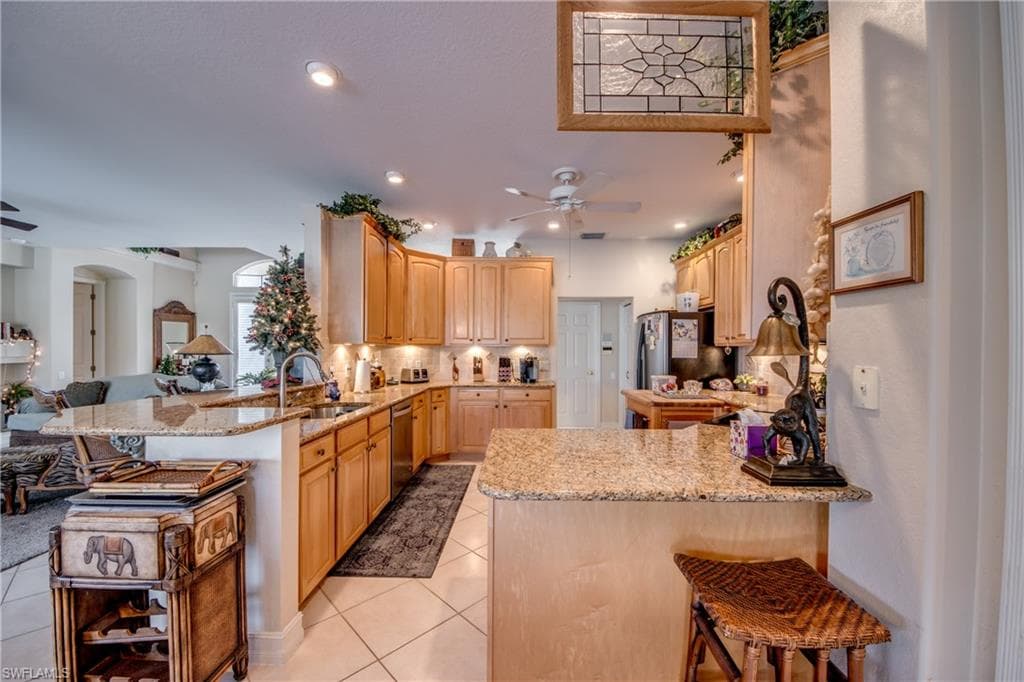 Kitchen featuring a breakfast bar, a peninsula, open floor plan, light stone counters, and backsplash