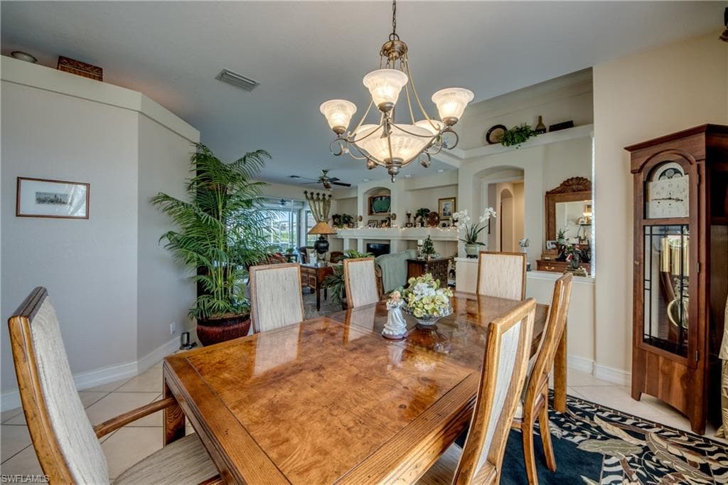 Dining room featuring suspended lighting, light tile patterned floors, arched walkways, and a fireplace