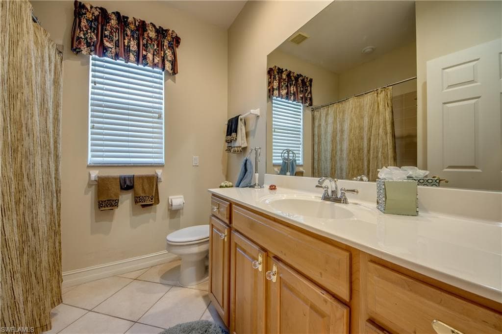 Bathroom with light tile patterned flooring, vanity, and curtained shower