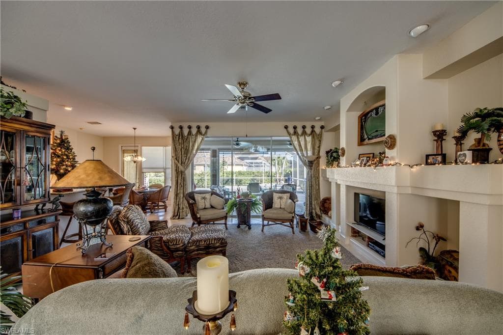 Living room featuring a glass covered fireplace, ceiling fan, and hanging lights