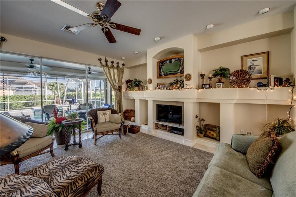 Living room with a sunroom, ceiling fan, and a glass covered fireplace