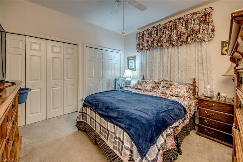Carpeted bedroom featuring two closets and a ceiling fan