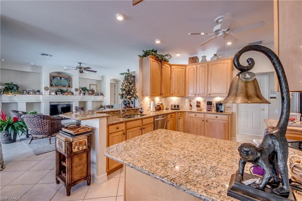 Kitchen featuring ceiling fan, light wood finish cabinets, backsplash, open floor plan, and light tile patterned flooring