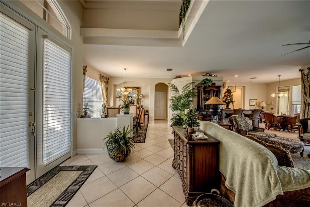 Living room with suspended lighting, arched walkways, healthy amount of natural light, and light tile patterned floors