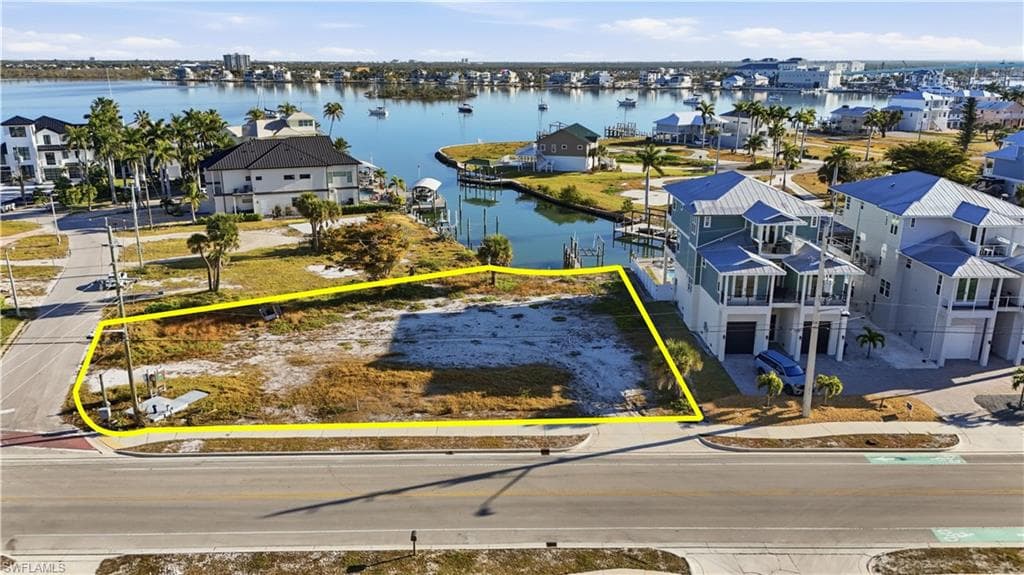 Aerial perspective of suburban area featuring property parcel outlined and a nearby body of water - Virtually Edited Image