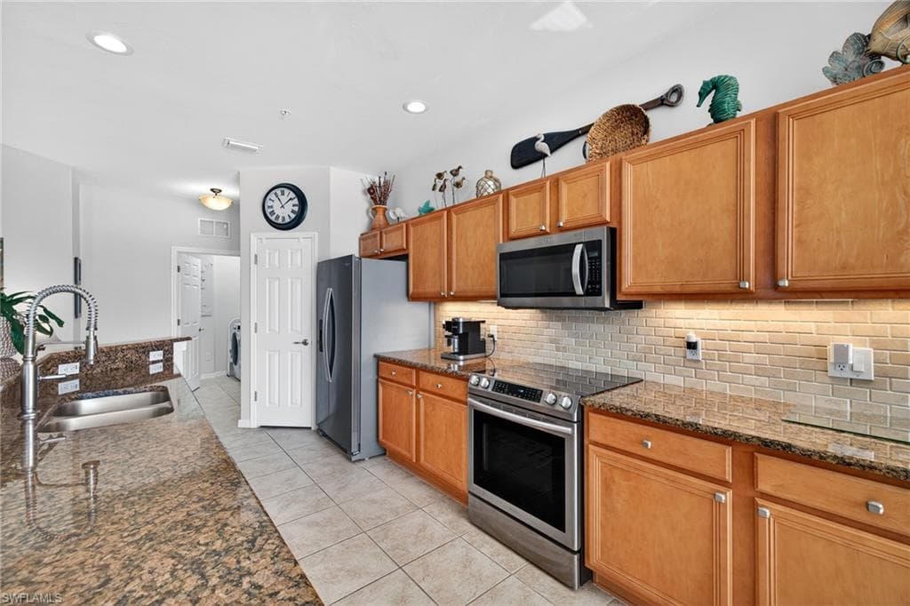 Kitchen with dark stone counters, wood finish cabinetry, and recessed lighting.