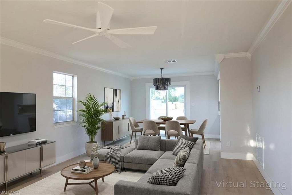 Living area featuring crown molding, light wood finished floors, ceiling fan, and hanging lights