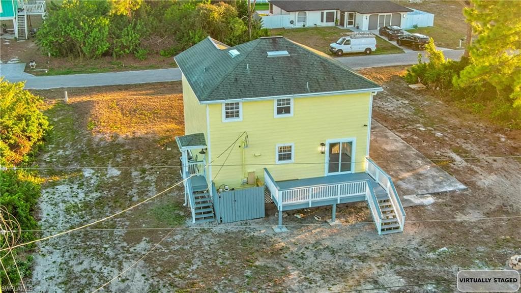 Rear view of property with stairs, a shingled roof, and a deck
