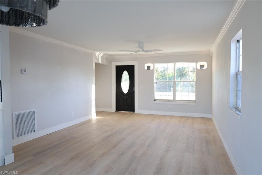 Entryway with ornamental molding, light wood-style floors, and ceiling fan