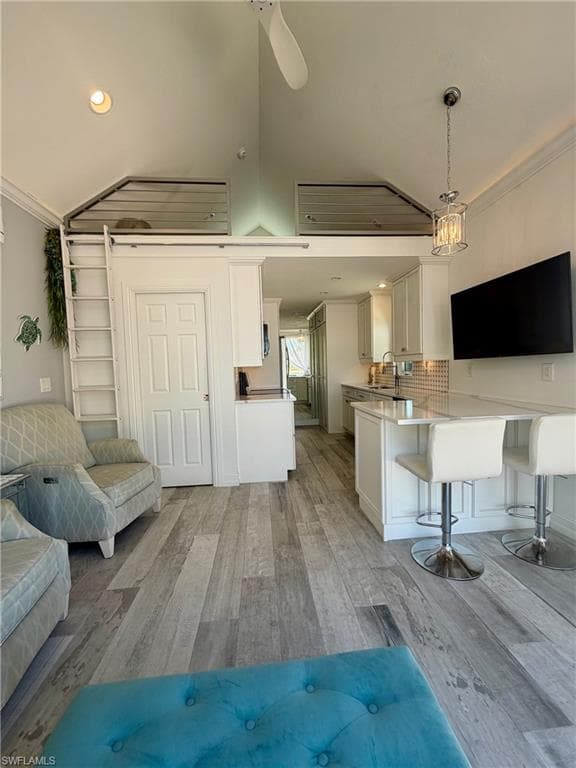 Living room with ornamental molding, light wood finished floors, recessed lighting, and vaulted ceiling