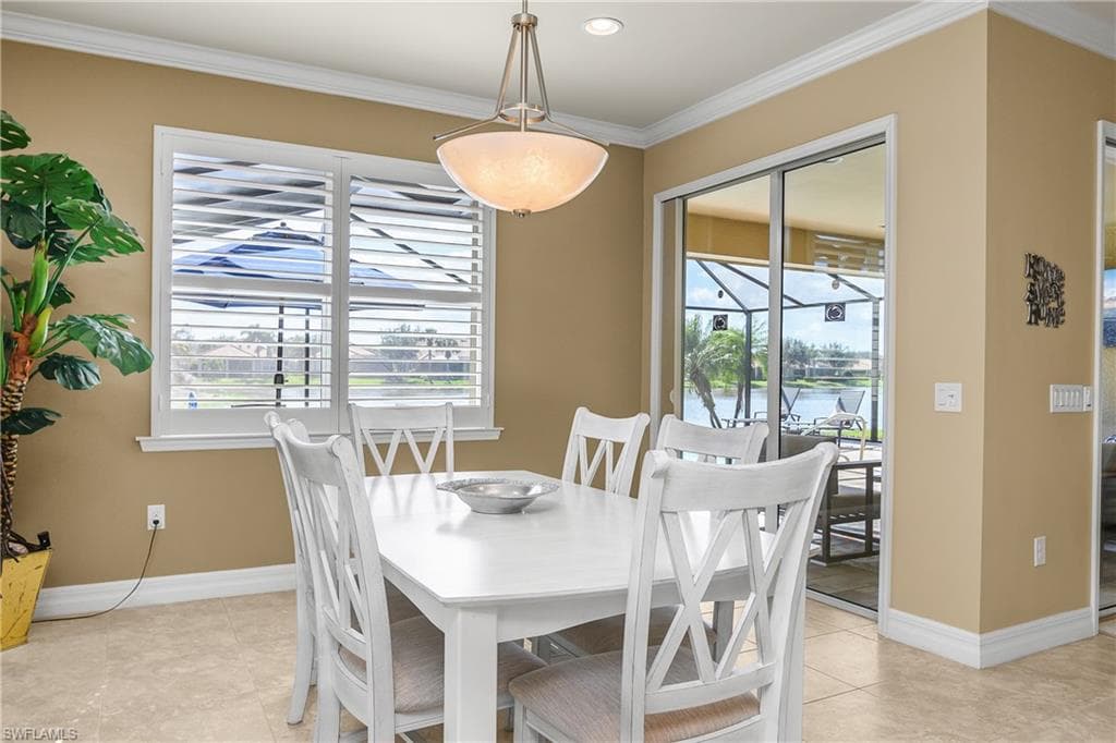 Dining area with ornamental molding, light tile patterned floors, and a water view