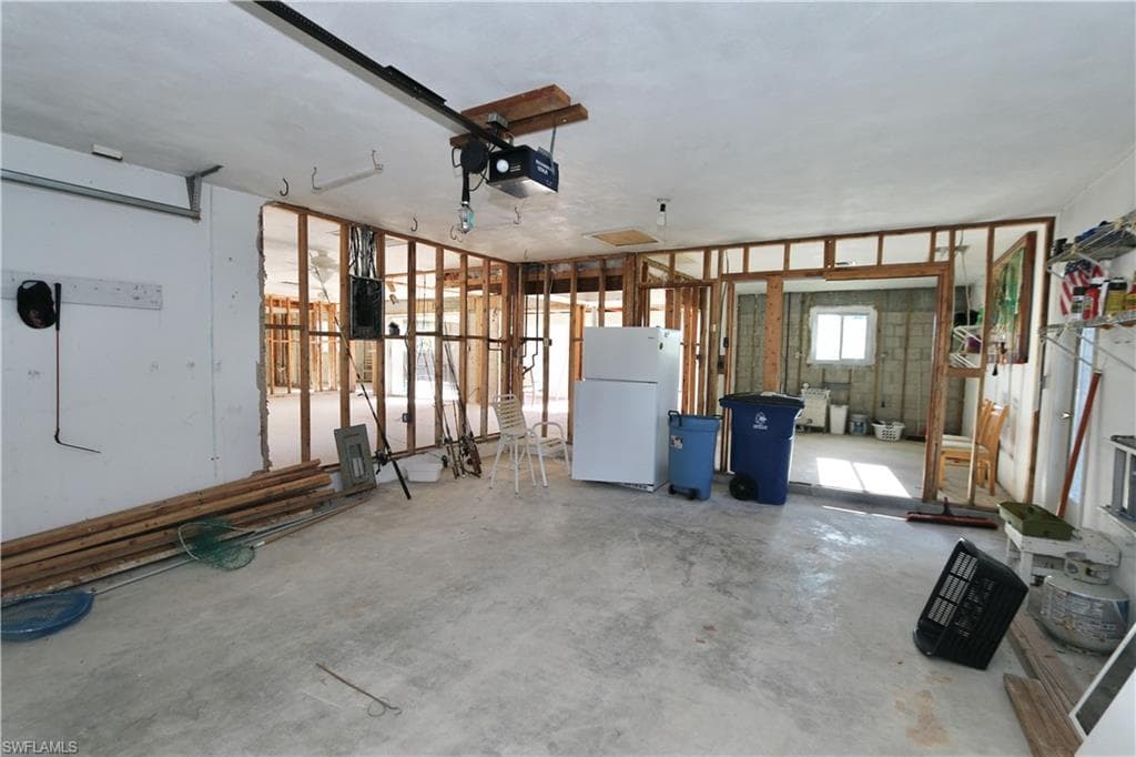 Garage with freestanding refrigerator and a garage door opener