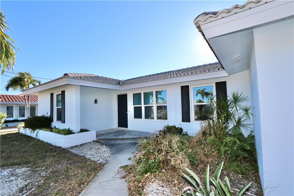 Property entrance featuring a tiled roof and stucco siding