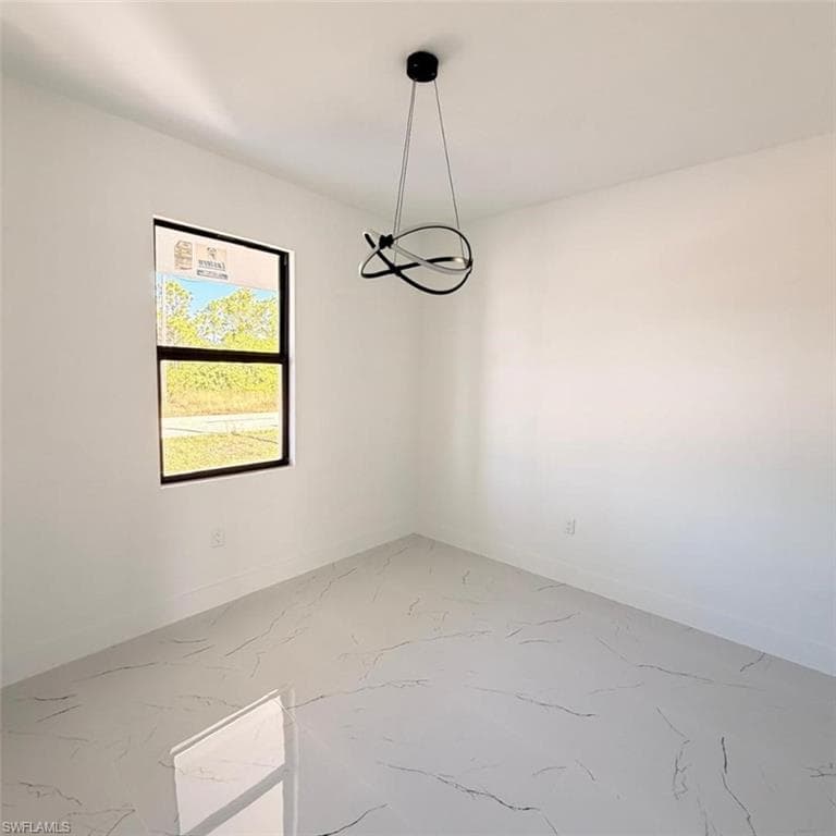 Empty room featuring light marble finish floors and baseboards