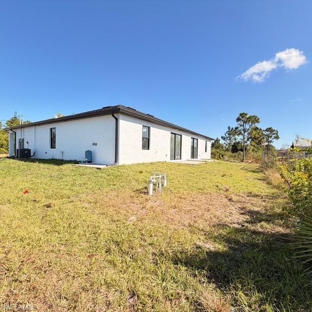 Rear view of property featuring stucco siding and a yard