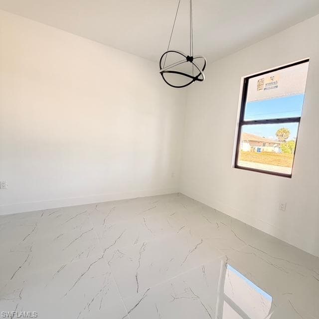 Unfurnished dining area with a chandelier and light marble finish floors