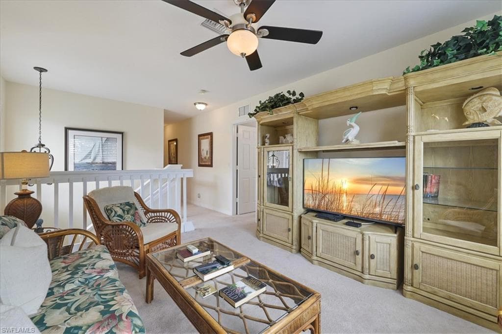 Living area with light colored carpet and a ceiling fan