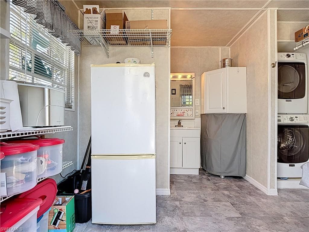 Laundry room featuring stacked washer and dryer and baseboards