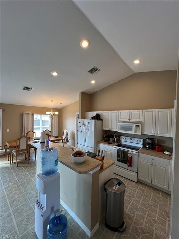 Kitchen with white appliances, white cabinets, a center island with sink, hanging lights, and vaulted ceiling
