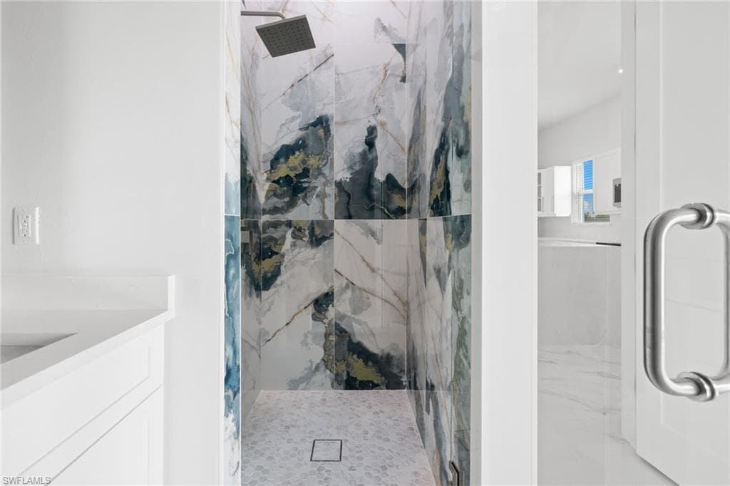 Full bathroom with a marble finish shower and vanity