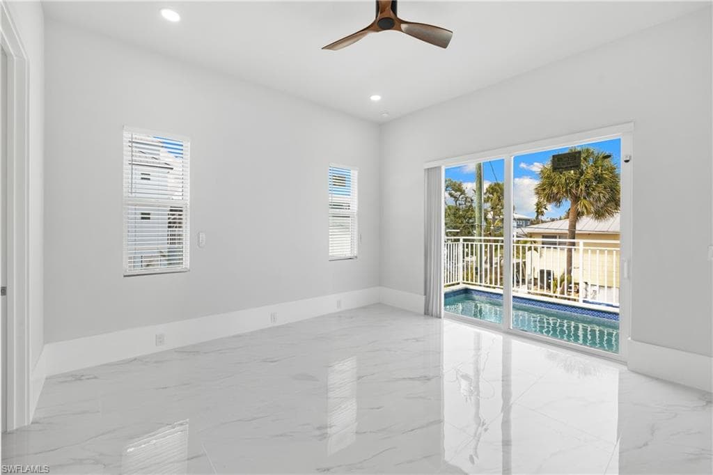 Unfurnished room featuring ceiling fan, plenty of natural light, light marble finish flooring, and recessed lighting