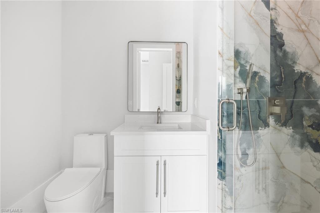 Full bath featuring a marble finish shower and vanity