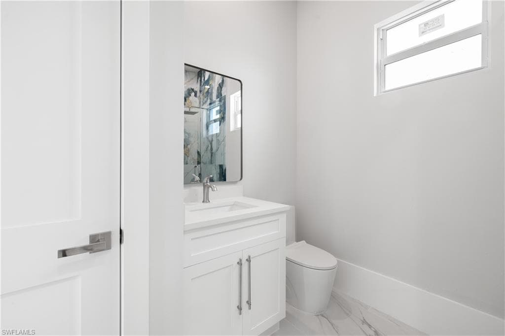 Half bathroom with vanity and light marble finish floors