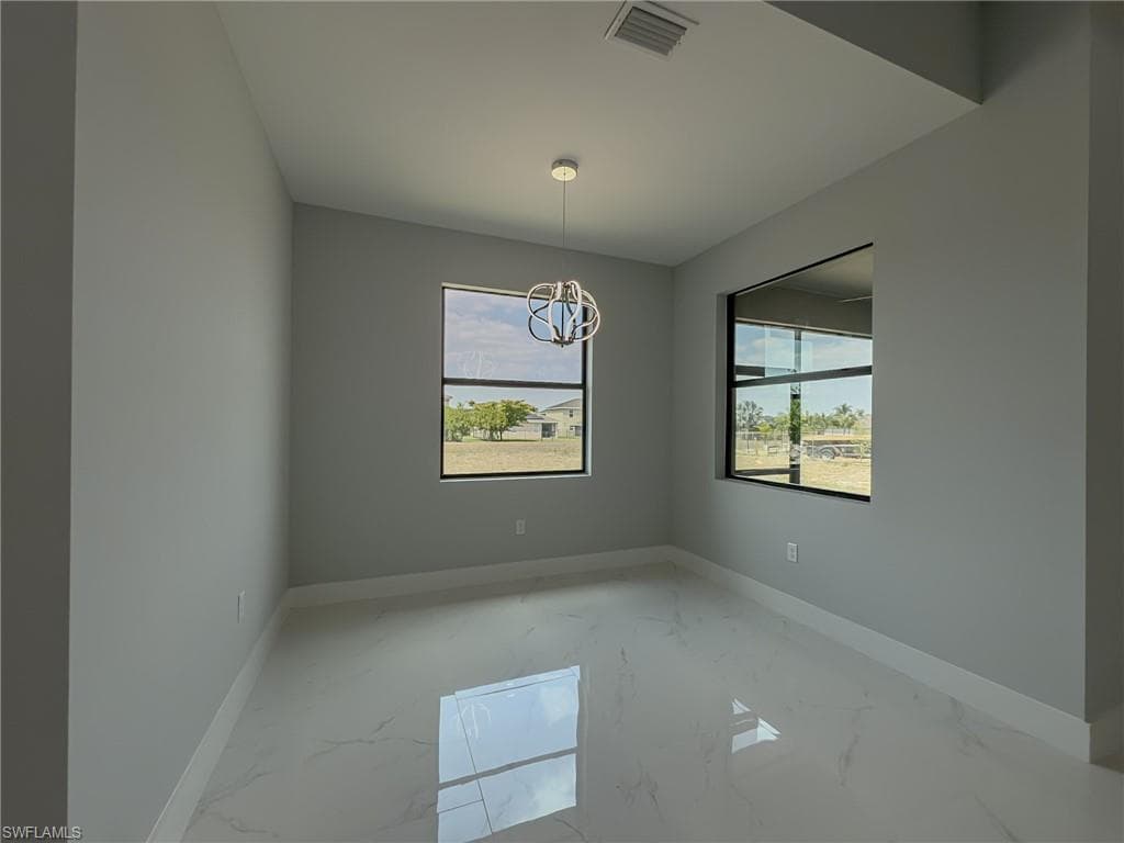 Unfurnished room featuring marble finish floor, visible vents, a chandelier, and baseboards