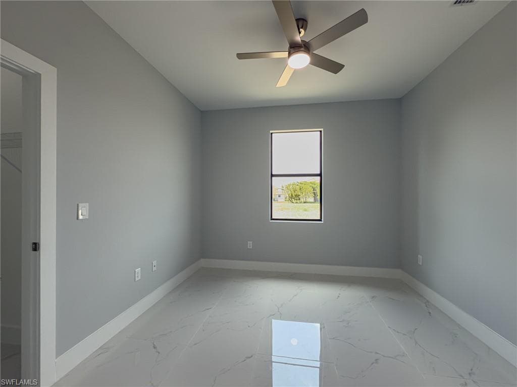 Spare room with ceiling fan, baseboards, and marble finish floor