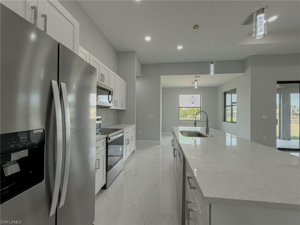 Kitchen featuring recessed lighting, a sink, a spacious island, marble finish floor, and appliances with stainless steel finishes