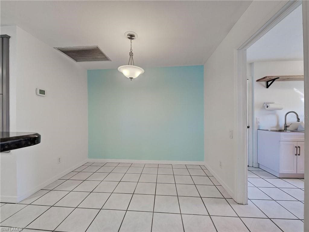 Unfurnished dining area with light tile patterned flooring and baseboards