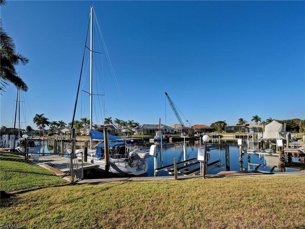 Dock area with a lawn, boat lift, a water view, and a residential view