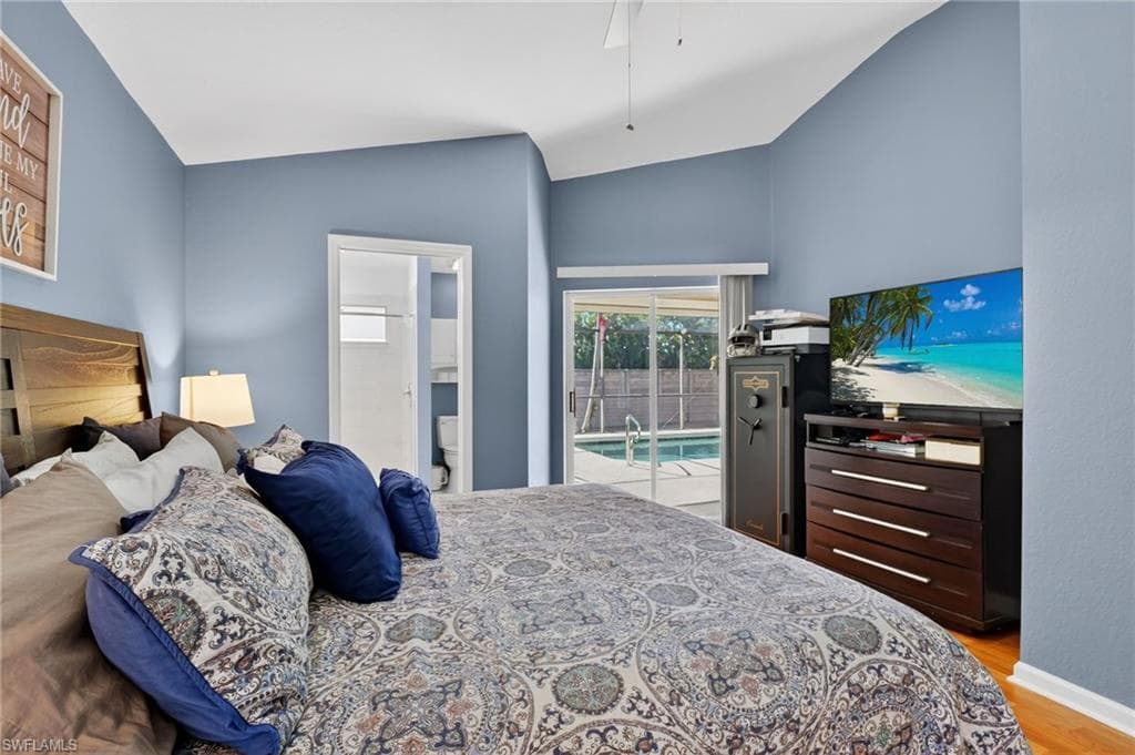 Bedroom featuring access to outside, vaulted ceiling, a ceiling fan, connected bathroom, and light wood finished floors