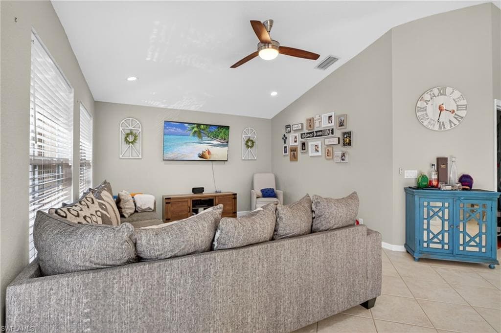 Living area featuring a ceiling fan, recessed lighting, light tile patterned floors, and vaulted ceiling