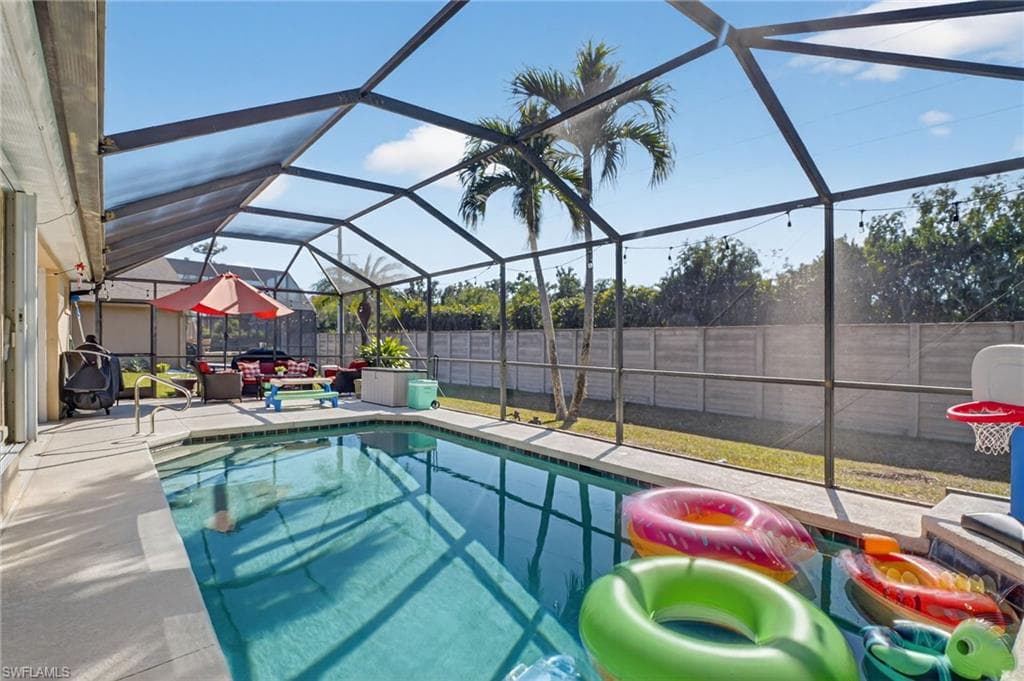 View of swimming pool with a fenced backyard, a sunroom, a lanai, and patio surround