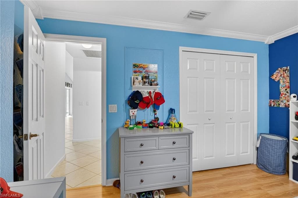 Bedroom with a closet, light wood finished floors, and crown molding