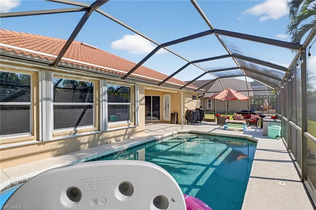 Swimming pool featuring a sunroom, a patio area, and glass enclosure