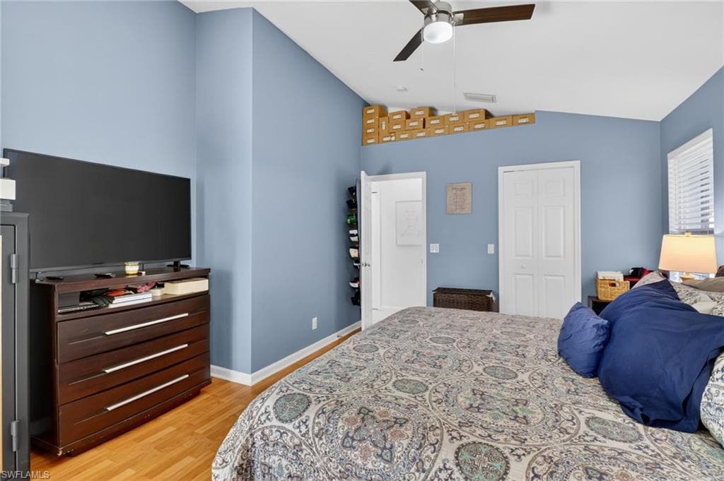 Bedroom with a closet, light wood-style floors, a ceiling fan, and lofted ceiling