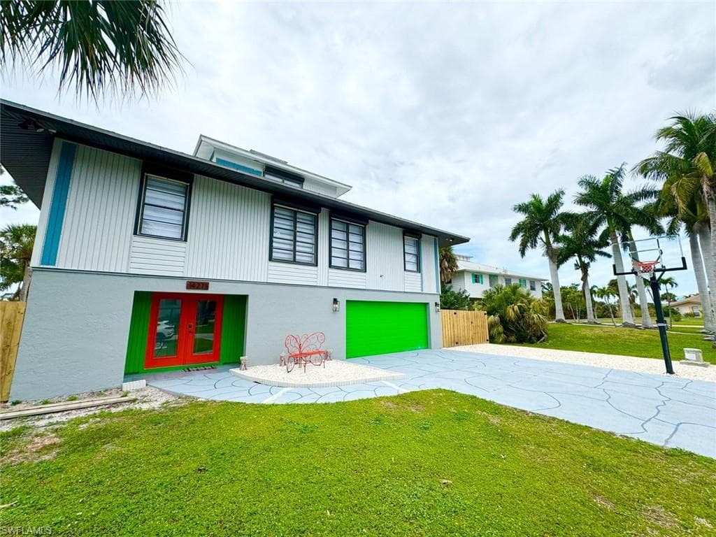 Back of house featuring an attached garage, driveway, french doors, and stucco siding