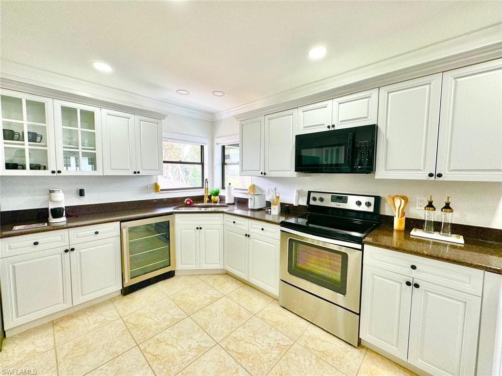Kitchen with electric stove, white cabinets, black microwave, crown molding, and recessed lighting