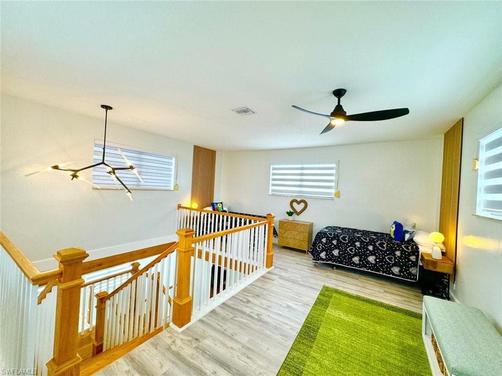 Bedroom featuring wood finished floors, a ceiling fan, and a chandelier