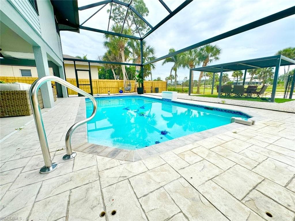 View of swimming pool featuring patio surround, glass enclosure, a sunroom, and a fenced backyard