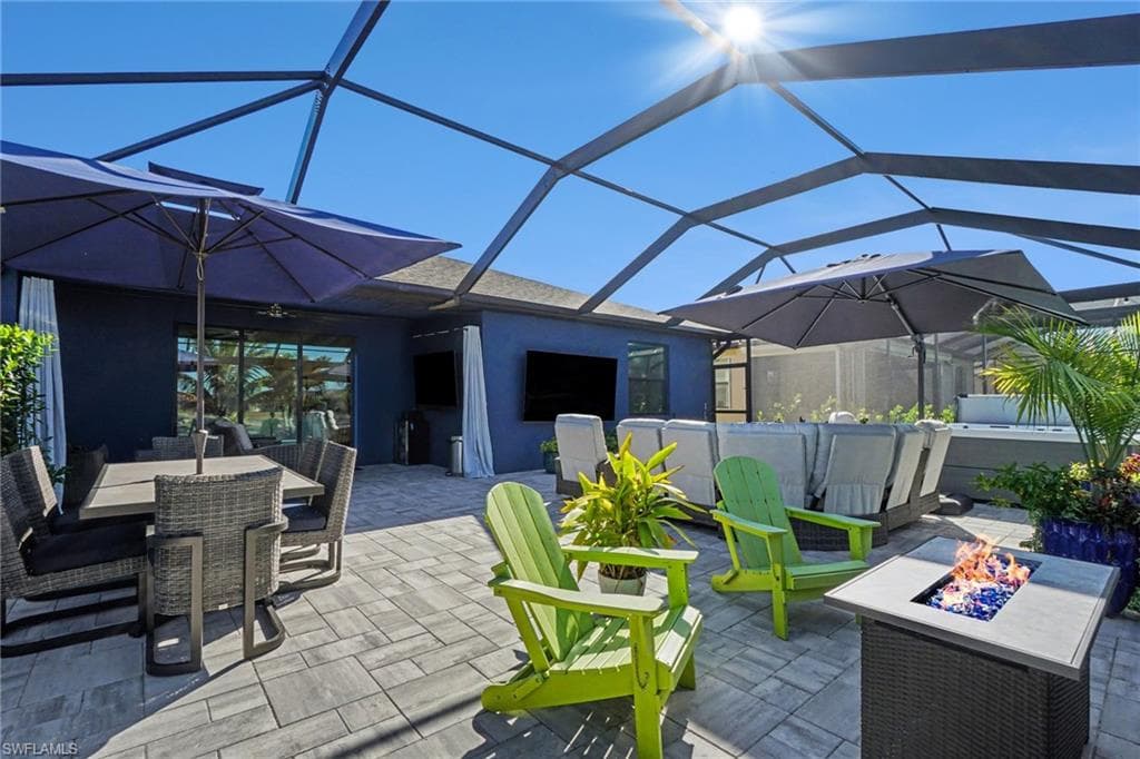 View of patio / terrace featuring glass enclosure, outdoor dining area, a sunroom, and a fire pit