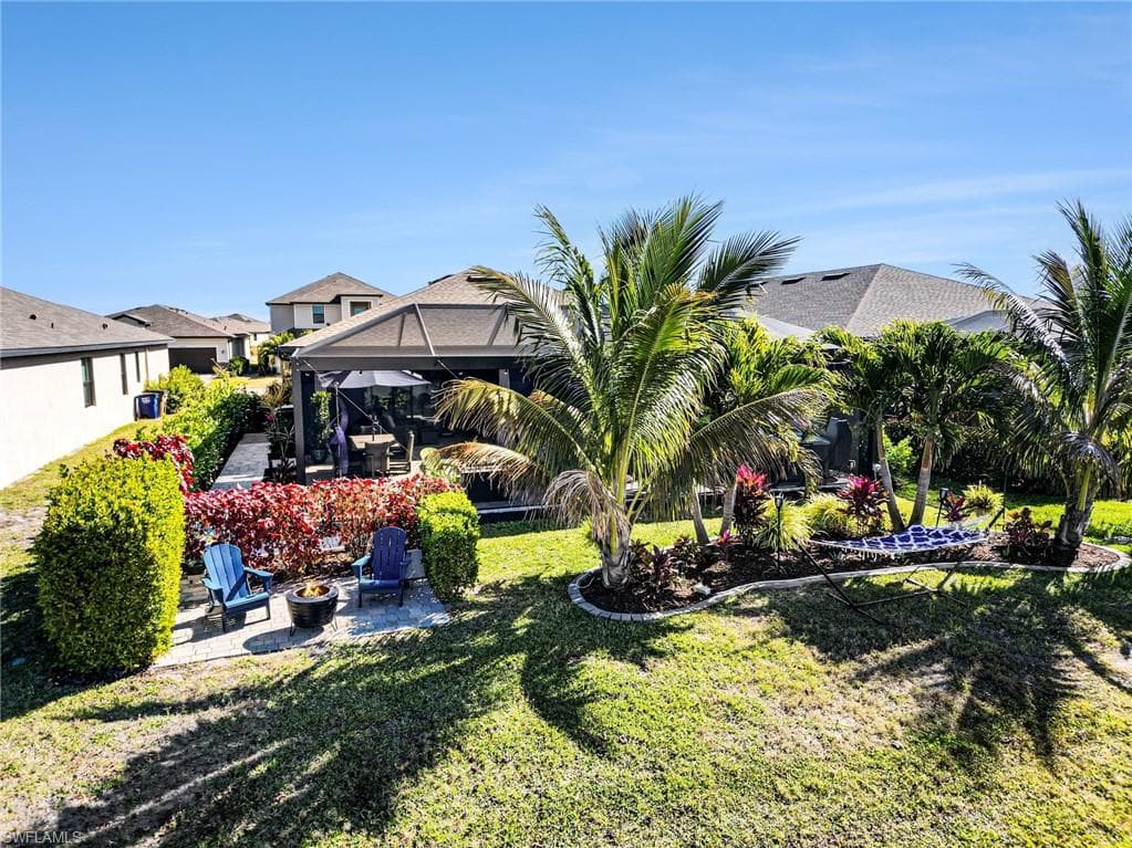 View of green lawn featuring a patio area, a lanai, and an outdoor fire pit