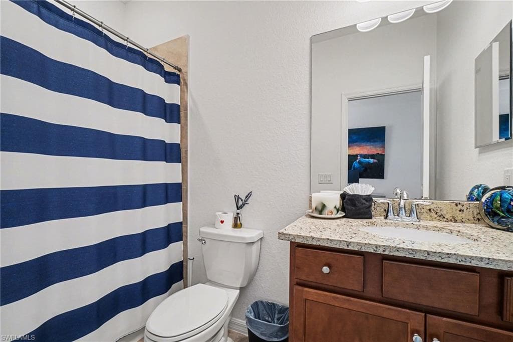Full bath with a textured wall, a shower with curtain, and vanity