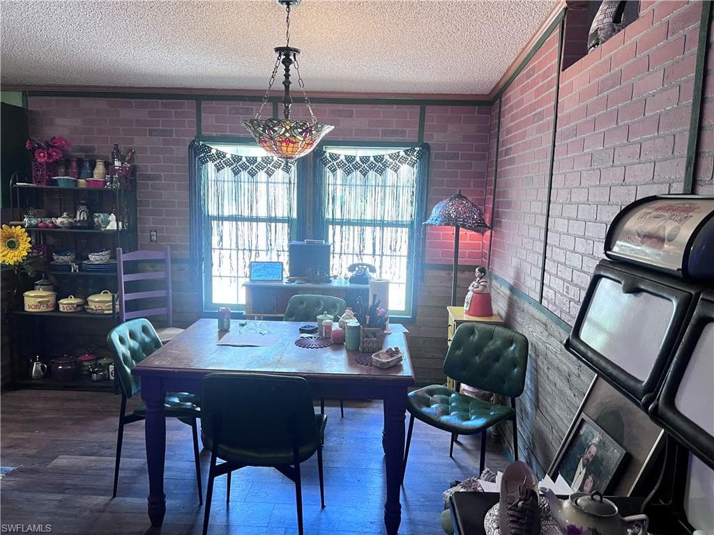 Dining area featuring wood finished floors, crown molding, a wood stove, and a textured ceiling