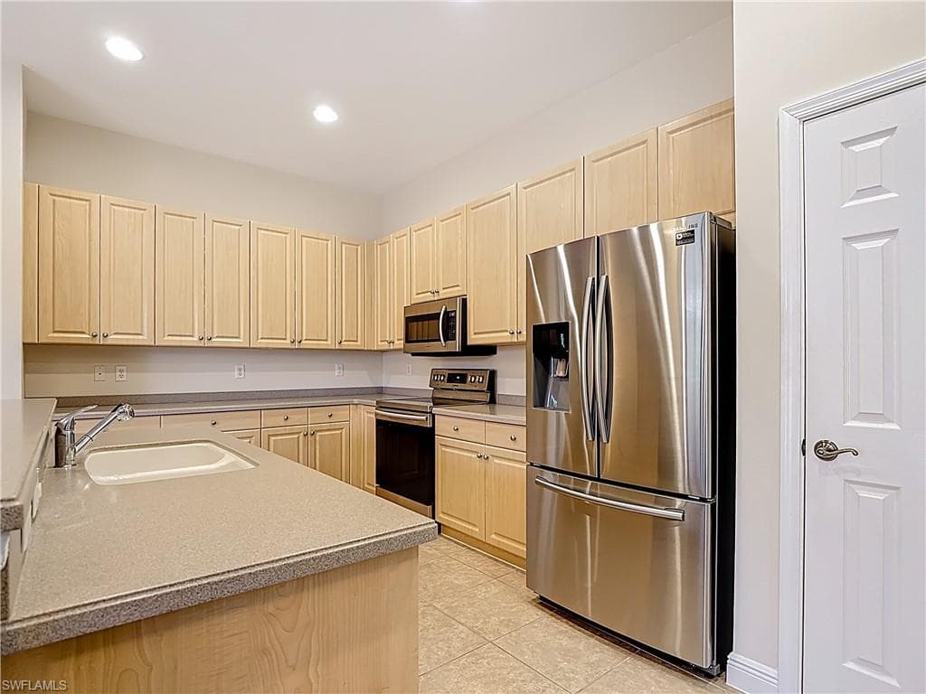 Kitchen with stainless steel appliances, recessed lighting, light wood finish cabinets, and light tile floors